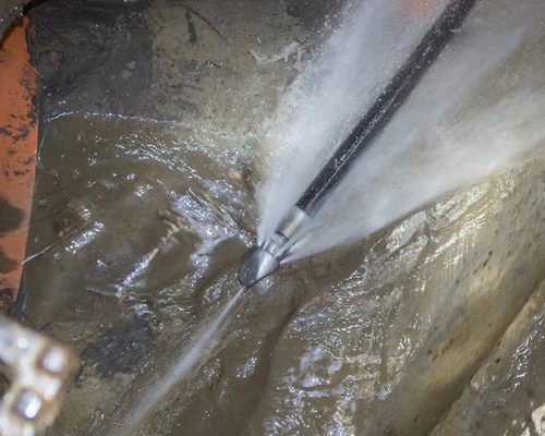 A high-pressure water jet from Bison Plumbing is forcefully cleaning the inside of a dirty sewer or drain pipe, showcasing the advanced No-Dig Sewer Repairs technique trusted by plumbers in Warren MI.